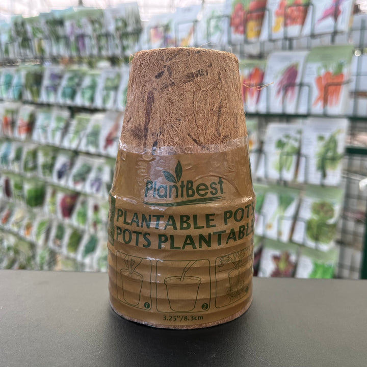 Plantable pot with 'PlantiBest' branding on a table with seed packets in the background.